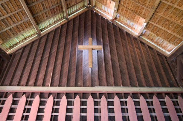 Illuminated wooden cross on wooden wall in outdoor chapel