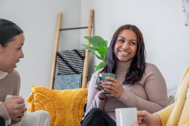 istock Three women enjoy a casual chat on the couch while sipping from their coffee mugs. 2175344573