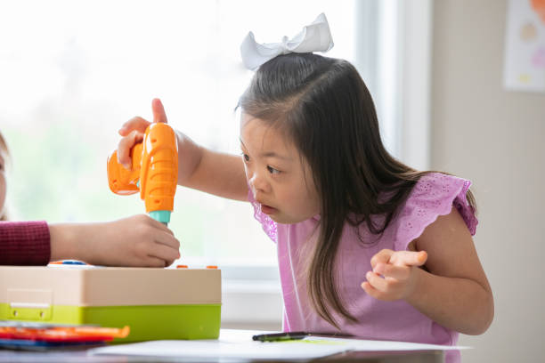 istock Curious student with Down Syndrome uses STEM educational building toy in special education classroom 2175352716