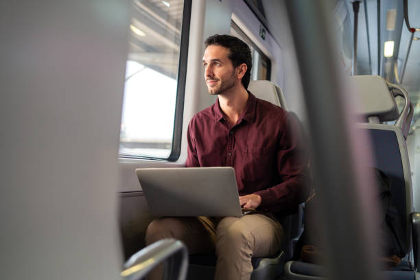istock Young professional happily works on his laptop while enjoying a train ride 2175357086