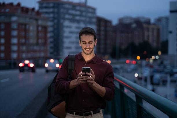 istock Young professional man happily walks home at night, using his smartphone 2175357180