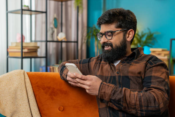 istock Happy Indian man thinking texting messaging on smartphone internet social media app on home sofa 2175361096