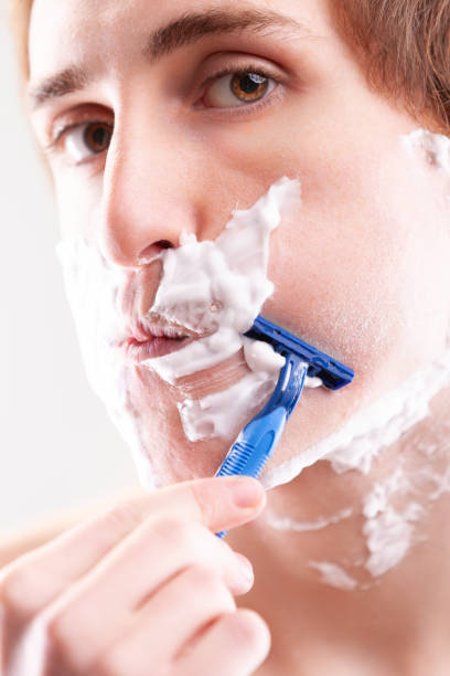 istock Young man carefully shaving face with razor 2175382617