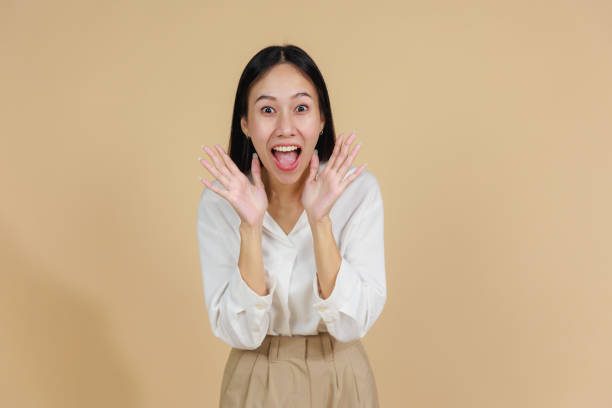 istock Excited Woman with Hands on Face, Beige Background 2175383748