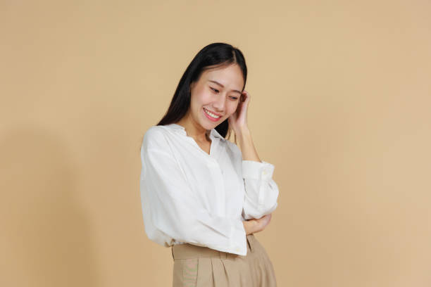 istock Shy Smiling Woman Touching Face with Bashful Expression, Beige Background 2175383834