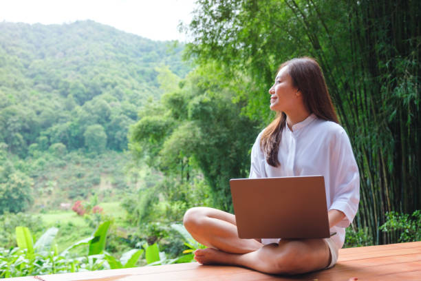 istock Portrait image of a woman using and working on laptop computer while sitting on balcony with a beautiful nature view 2175386650