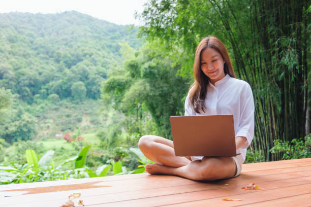 istock Portrait image of a woman using and working on laptop computer while sitting on balcony with a beautiful nature view 2175386654