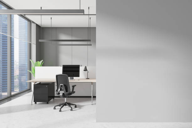 istock Grey workplace interior with pc monitors on tables in row, window. Mockup wall 2175391505