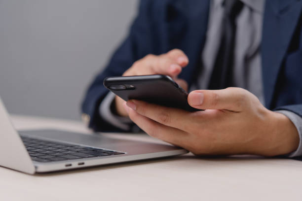 istock Businessperson using a smartphone and laptop, focusing on mobile communication and technology in business. Ideal for office, technology. 2175391869