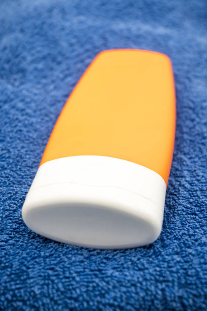 A yellow sunscreen tube sits on a sandy beach under bright sunlight, emphasizing sun protection and beach essentials in a tropical setting