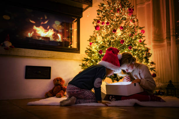 istock Children Unwrapping Christmas Present by the Tree 2175396946