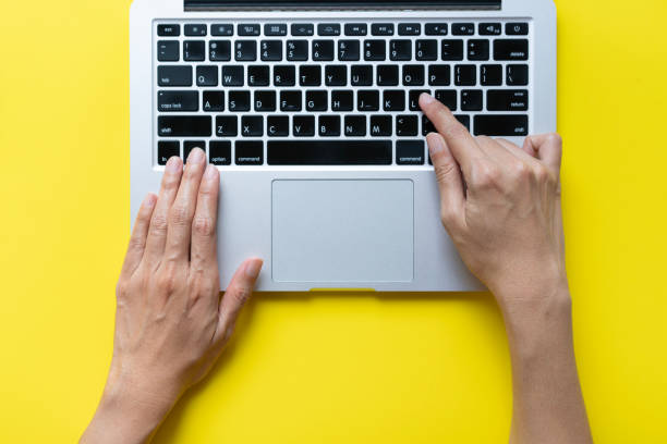 istock woman working on laptop while sitting in creative office or cafe on yellow table background, business concept. 2175399569