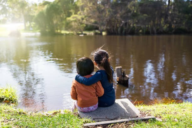two young girls enjoy looking at view on the river
