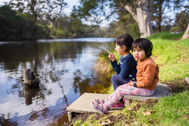 two young girls enjoy looking at view on the river