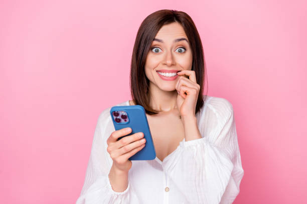istock Portrait of positive lovely cute lady freelancer using device smm post biting nail fingernail isolated on pink color background 2175409458