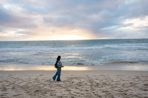 istock woman walking and looking out to sea 2175411207