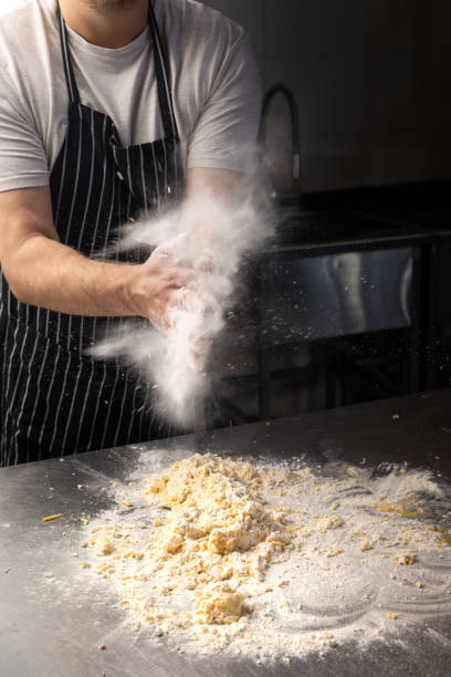 istock man chef in an apron prepares pasta in a restaurant kitchen. Kneads the dough with eggs. The process of preparing pasta dough. Noodles. Italian Cuisine. Recipe. 2175411249