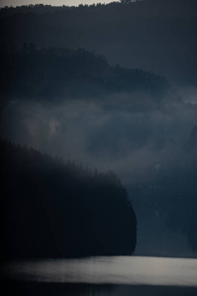 Forests and mountains misty landscape. Silhouettes of trees and clouds in a moody day in Norway