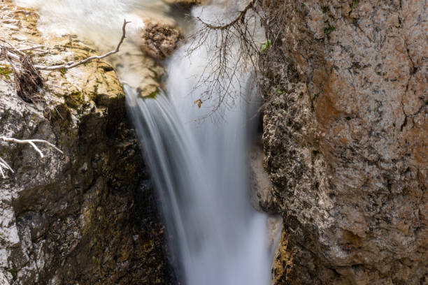 A detailed close-up of a waterfall cascading over rugged rocks, showcasing the dynamic motion of water and the texture of the surrounding stone.