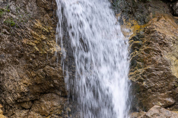 A detailed close-up of a waterfall cascading over rugged rocks, showcasing the natural texture of the stone and the flowing water in motion.