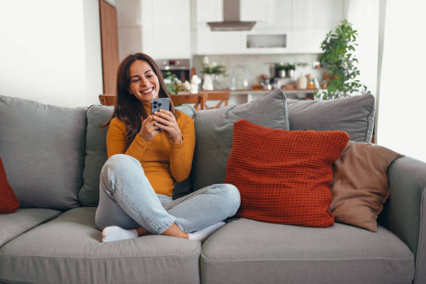 istock Woman Relaxing At Home Using Smartphone On Couch 2175459559
