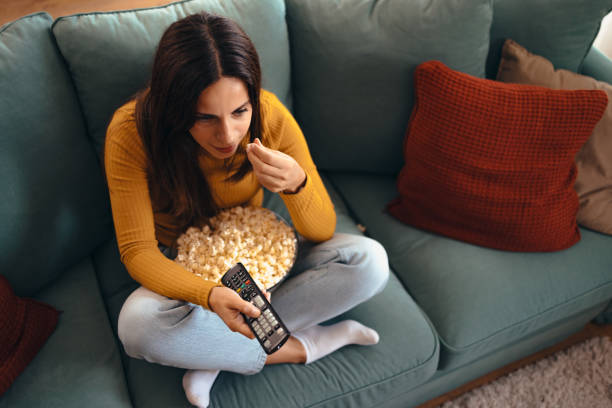 istock Woman Relaxing on Sofa Watching TV with Popcorn 2175459793