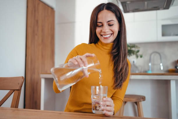 istock Woman Pouring Water into Glass in Modern Kitchen 2175459842