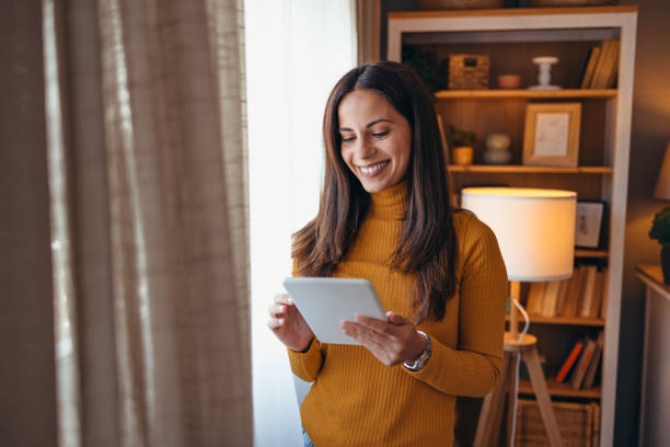 istock Smiling Woman Using Tablet in Cozy Living Room Setting 2175459951