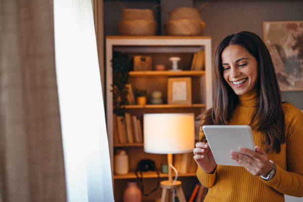 istock Smiling Woman Using Tablet in Cozy Living Room Setting 2175459953