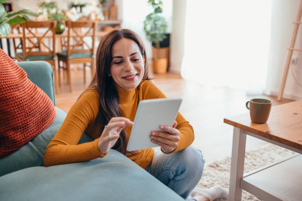 istock Smiling Woman Using Tablet in Cozy Living Room Setting 2175460097