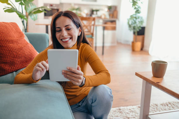 istock Smiling Woman Using Tablet in Cozy Living Room Setting 2175460117