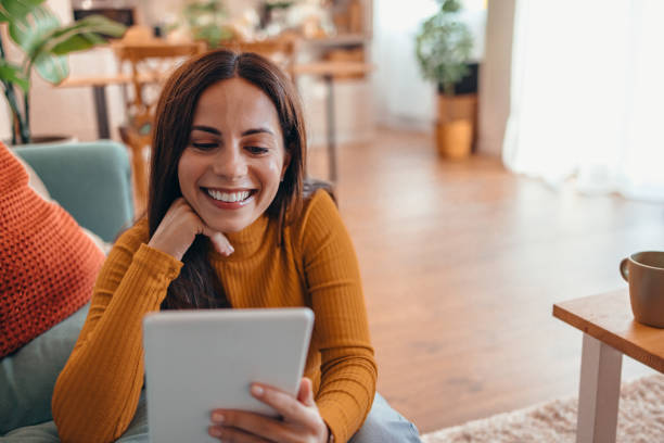 istock Smiling Woman Using Tablet in Cozy Living Room Setting 2175460133