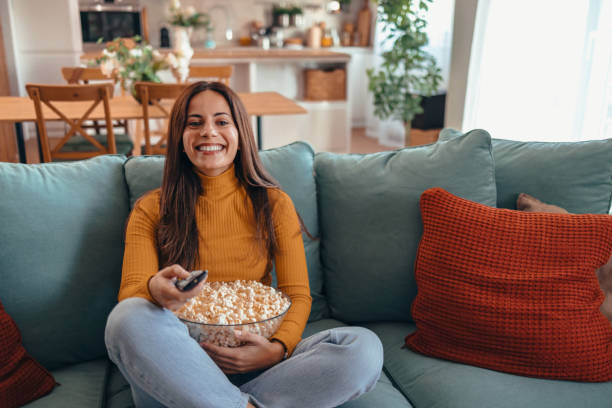 istock Woman Relaxing on Sofa Watching TV with Popcorn 2175460176