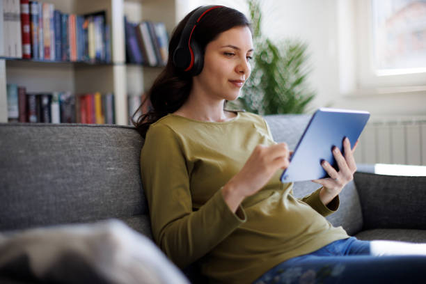 istock Smiling young woman with headphones using digital tablet at home 2175461891