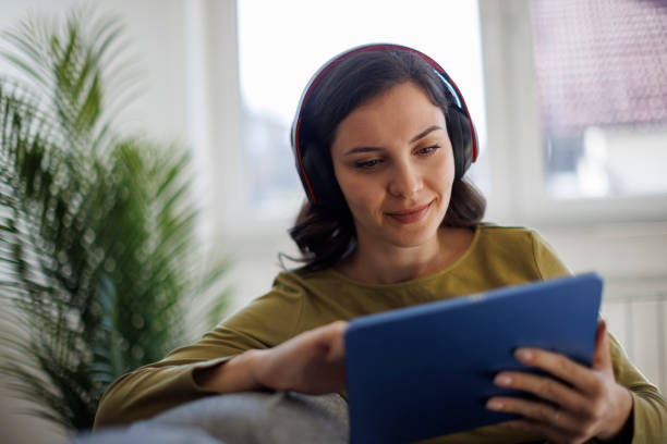 istock Smiling woman relaxing with digital tablet on couch at home 2175461893
