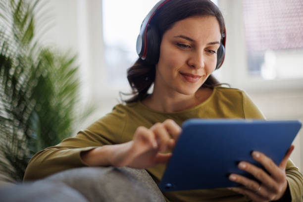 istock Smiling woman relaxing with digital tablet on couch at home 2175461898
