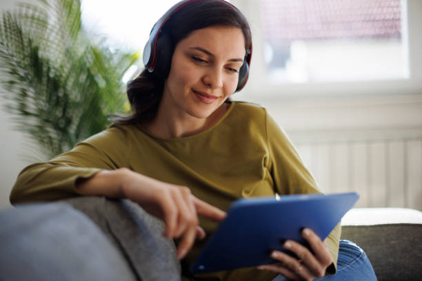 istock Smiling woman relaxing with digital tablet on couch at home 2175461914