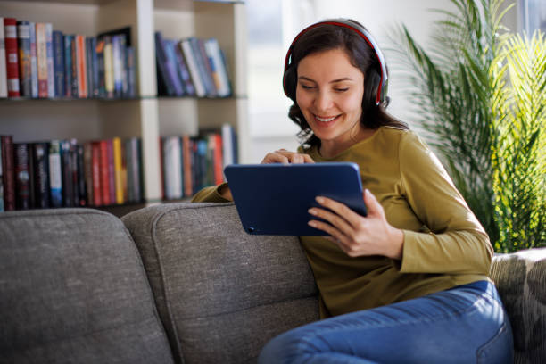 Smiling woman relaxing with digital tablet on couch at home