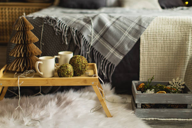 Cup of hot coffee on wicker rattan tray, boucle cosmetic bag, cosmetics on white bed linen. Spring mood. Home light beige interior decor.