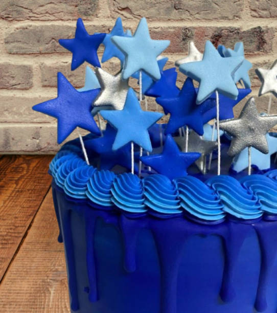 Blue birthday cake with drip and decorative stars.