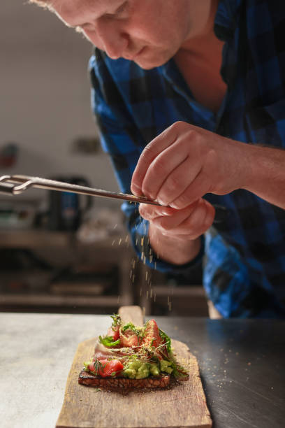 istock A chef prepares bruschetta with ham and avocado. Adding the final touch, he garnishes the dish with grated lemon zest. 2175472193