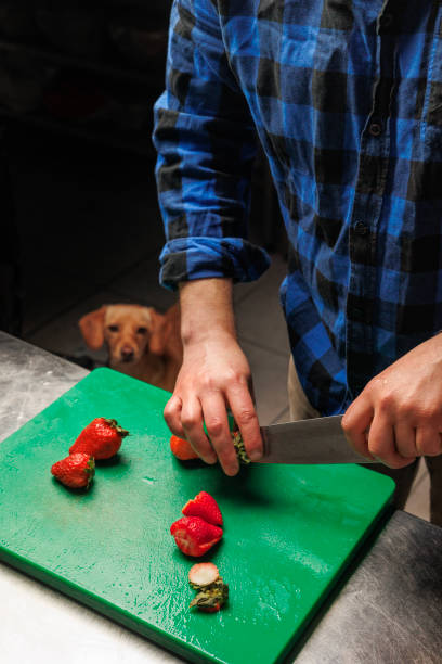 istock A man slices strawberries on a green cutting board while his loyal ginger dog observes the process, creating a charming kitchen scene 2175472678