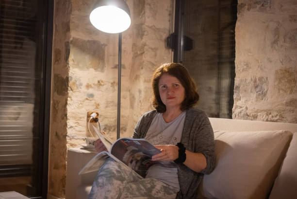 istock Mature moman reading magazine in stone house at evening 2175485879