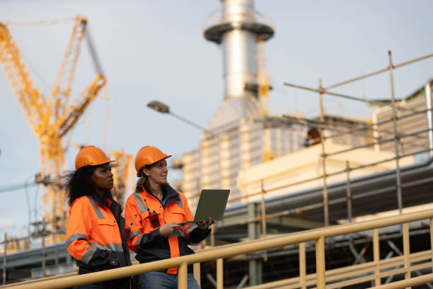 istock International women's day. Two brilliant female engineers engaged in a dynamic discussion at a bustling refinery plant in the heart of the industry. Embracing diversity and driving innovation in engineering. 2175487778