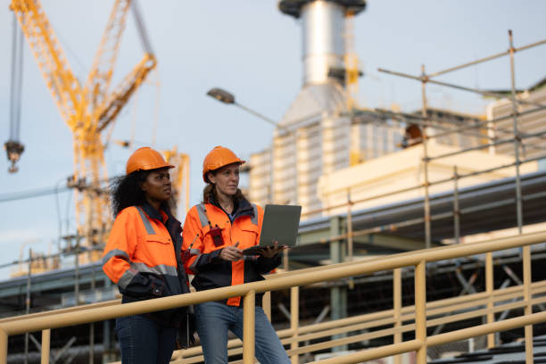 istock International women's day. Two brilliant female engineers engaged in a dynamic discussion at a bustling refinery plant in the heart of the industry. Embracing diversity and driving innovation in engineering. 2175487800