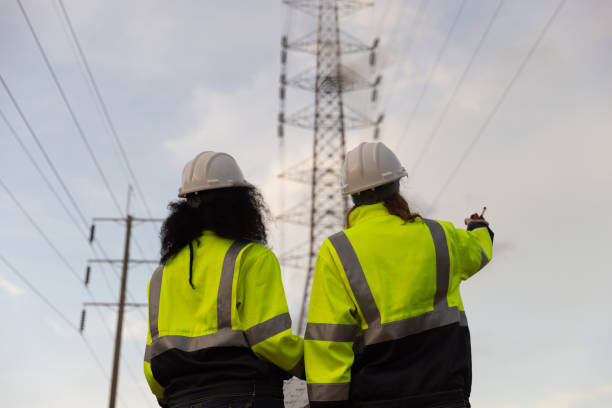 istock Back view of two female industry engineers working and discussing in front of a voltage-generating station and  high voltage pole 2175487840