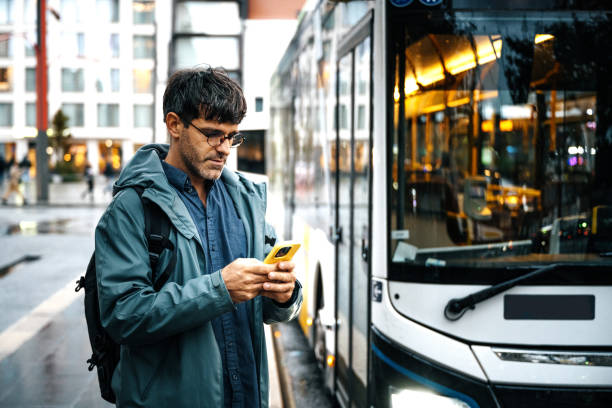 istock Mid adult commuter coming back from work on cloudy and rainy day and using smart phone while waiting for the bus ride 2175487931