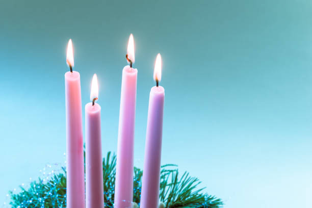 four white advent candles, four advent candles with light, dark black background