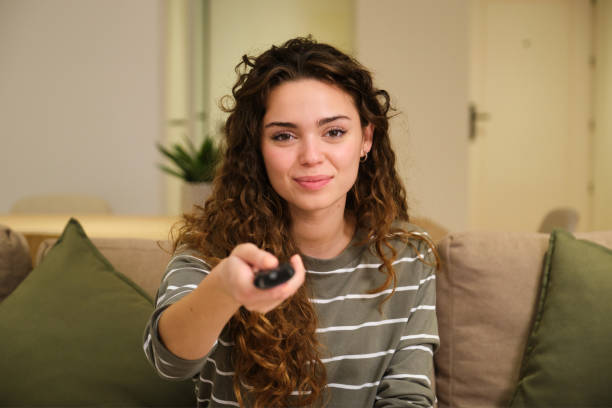 istock Woman relaxing on couch holding remote control watching television 2175492483