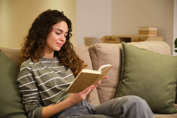 istock Young woman enjoying a book on a cozy sofa at home 2175492621